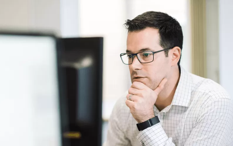 Image showing a man thinking at desk with his hand holding his chin