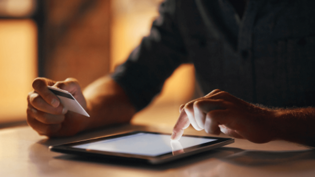 Man using tablet holding credit card